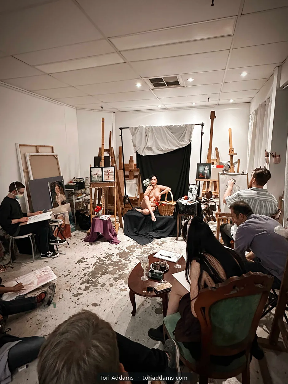 A group of artists drawing Tori in a life-drawing class