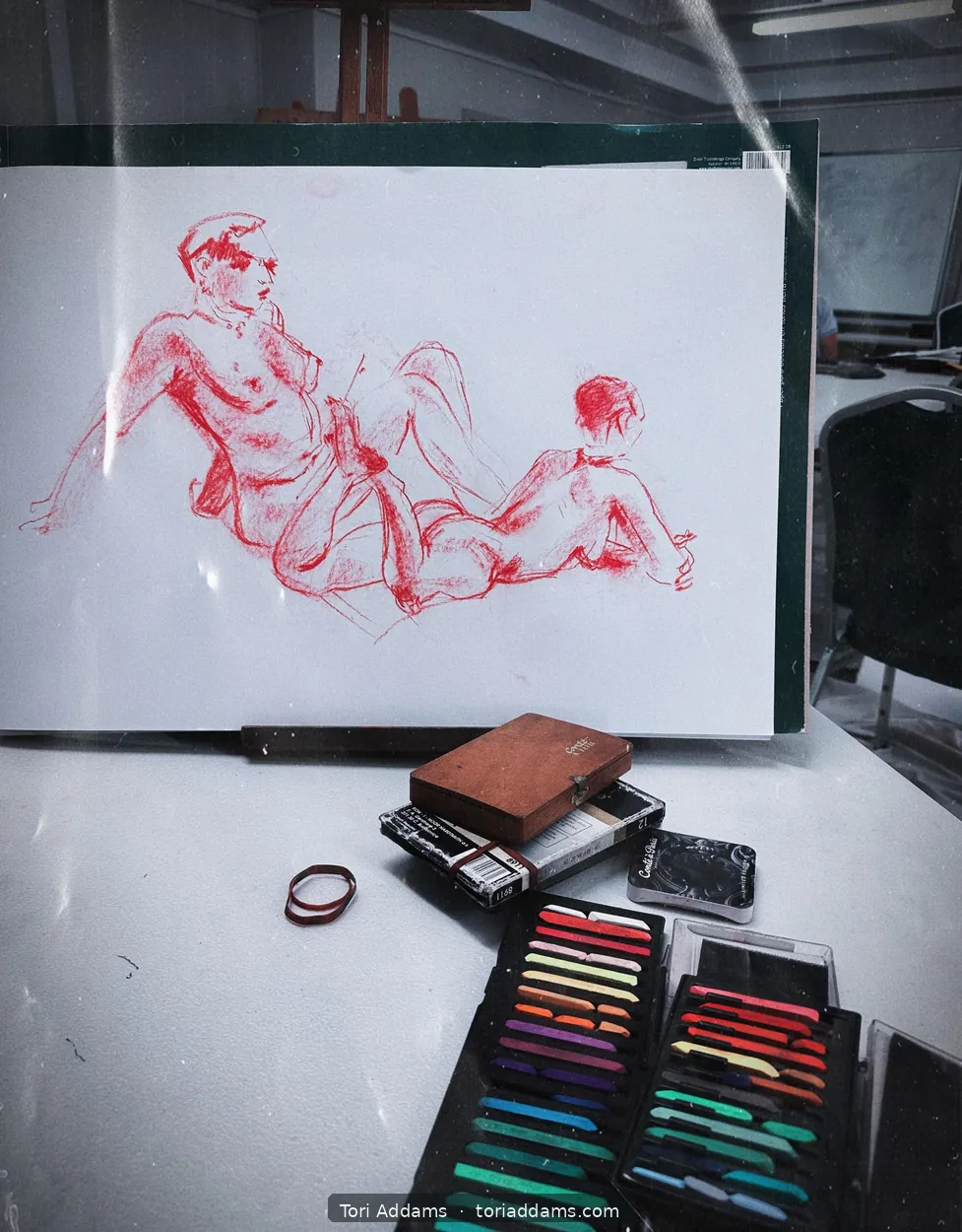 Red pastel life-drawing studies alongside artists' materials